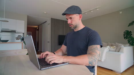 Man-Sitting-by-His-Desk-and-Working-on-a-Laptop-Wide-Shot