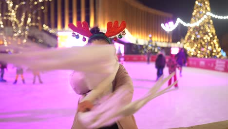 mujer con cuernos de reno disfrutando de patinaje sobre hielo por la noche