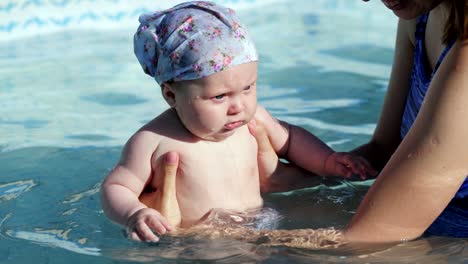 mother holding her daughter and she having fun in swimming pool