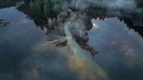 aerial view of secluded scenic lake and foggy trees at sunrise