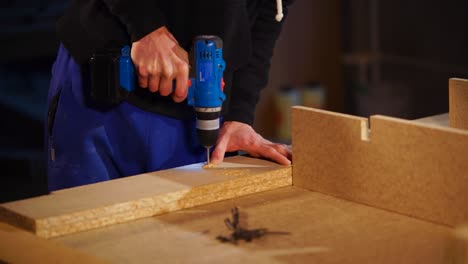 persona que utiliza un taladro eléctrico para montar paneles de madera
