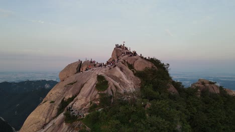 Toma-Aérea-Sobrevolando-La-Cumbre-De-La-Montaña-Bukhansan-Con-Turistas-Y-Excursionistas