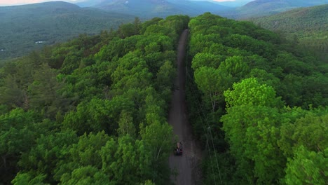 imágenes de drones de un coche con una canoa conduciendo por las montañas blancas de nh a través del bosque en un camino de tierra