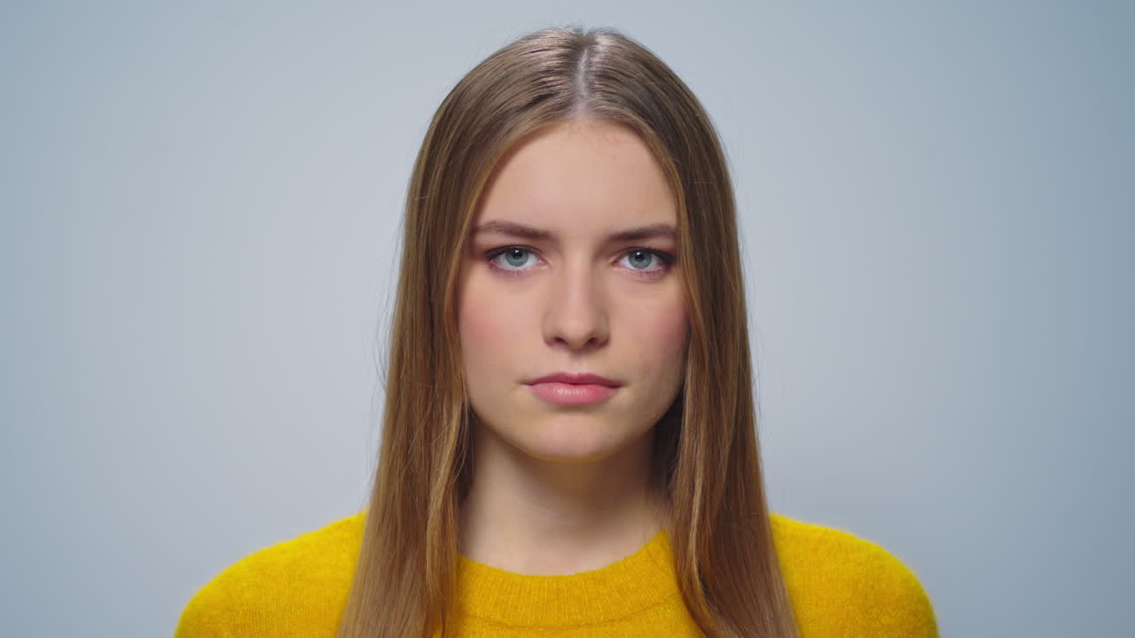 портрет серьезной женщины, позирующей на сером фоне в студии.