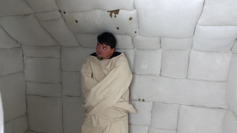 man in straightjacket in padded room