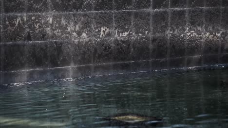 Ruhiger-Wandbrunnen-Mit-Wasserspiel,-Der-In-Einen-Ruhigen-Teich-Mündet