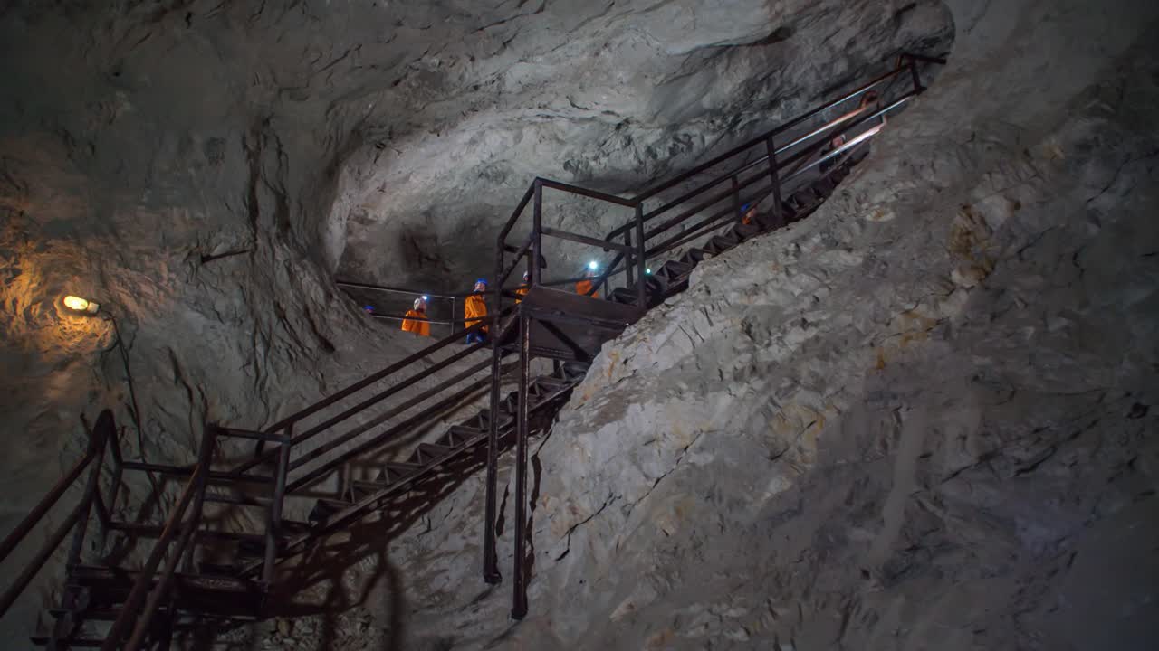 Underground Miners Wearing Headlamps Walk Through Cave