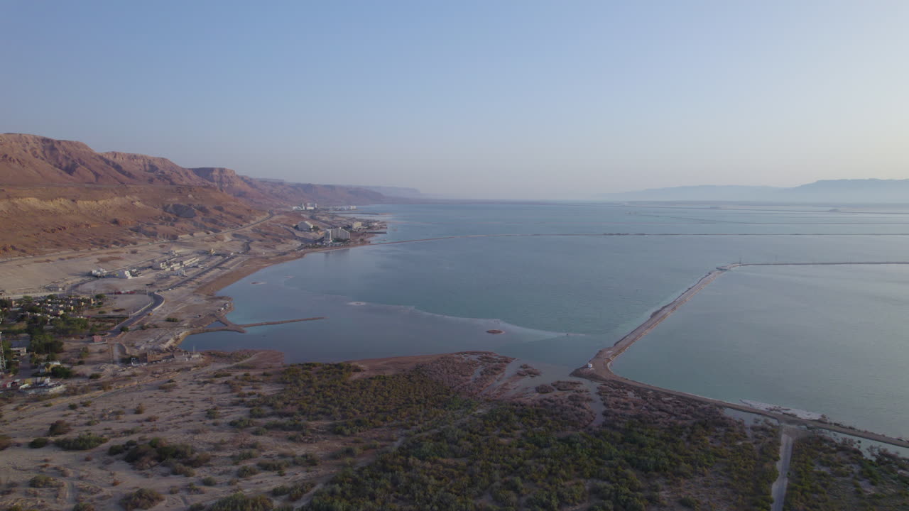 An area with green blooms next to the Dead Sea with the hotels in the background