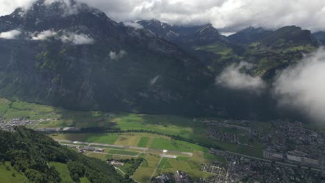 Fronalpstock-Glarus-Switzerland-aerial-above-village-pan-down-with-shadows-from-clouds