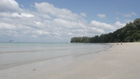 Der-Strand-Mit-Ein-Paar-Yachten-Im-Meer,-Weißer-Sand-Und-Wellen-Vom-Ruhigen-Meer-Bei-Sonnenschein-Tagsüber