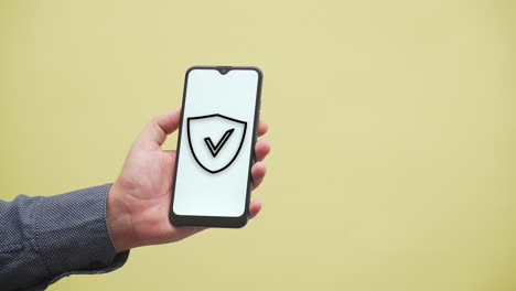 la mano muestra un escudo con un icono de marca de verificación en un teléfono inteligente