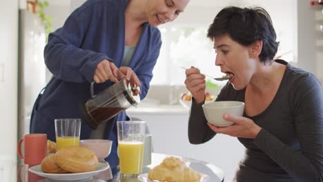 백인 여성 이 집 에서 아내 와 함께 아침 식사를 하는 동안 컵 에 커피 를  ⁇ 고 있다