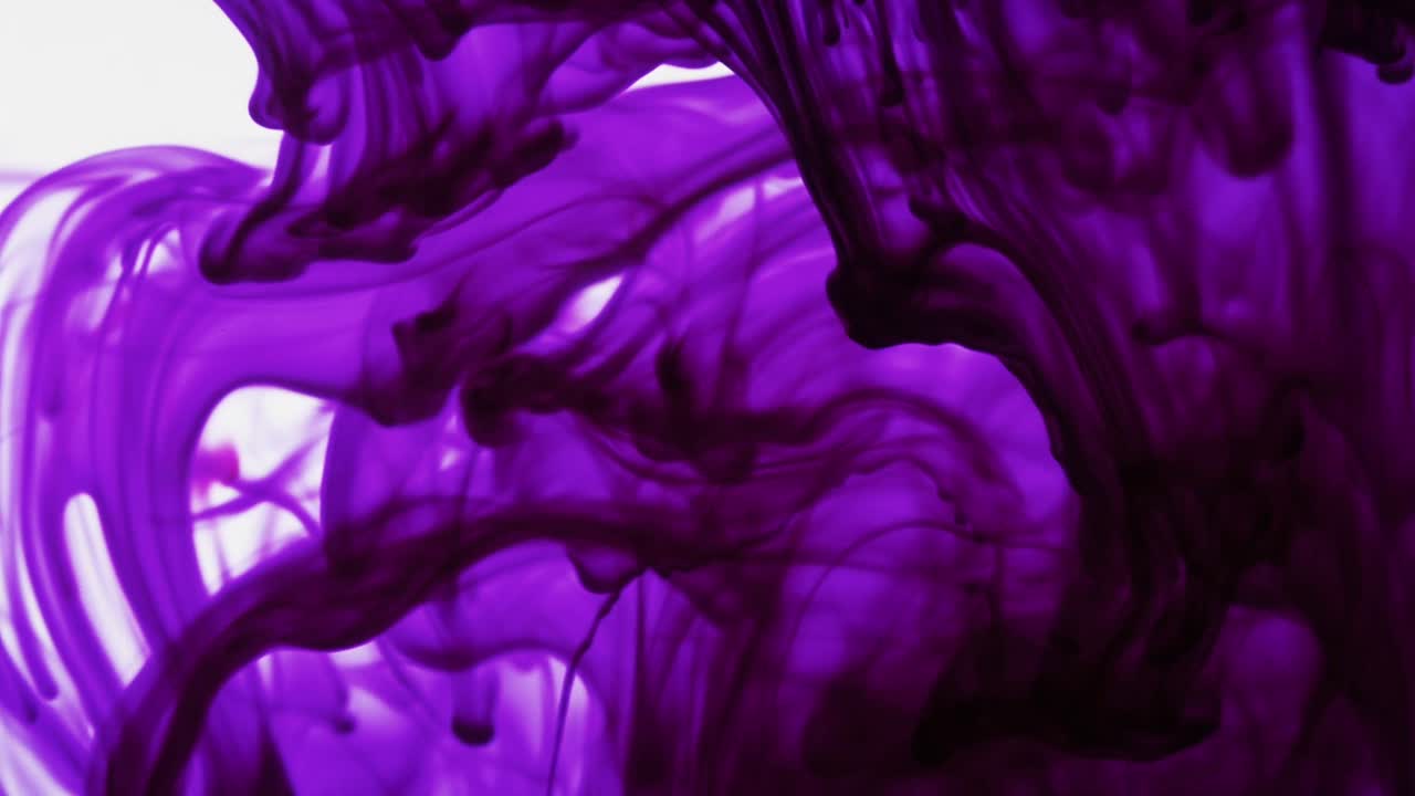 Colorful chemical liquids mix and swirl in water, forming smooth abstract patterns and organic shapes