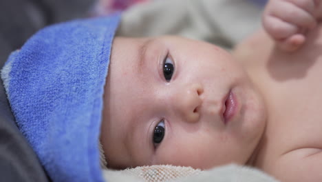 charming baby face opening his little mouth periodically. lovely kid face covered with towel after bathing time. close up.