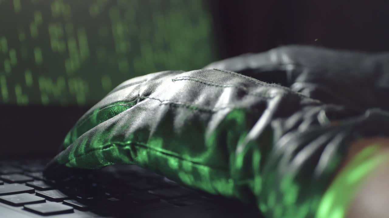 Computer hacker wearing black gloves on a laptop keyboard close up shot