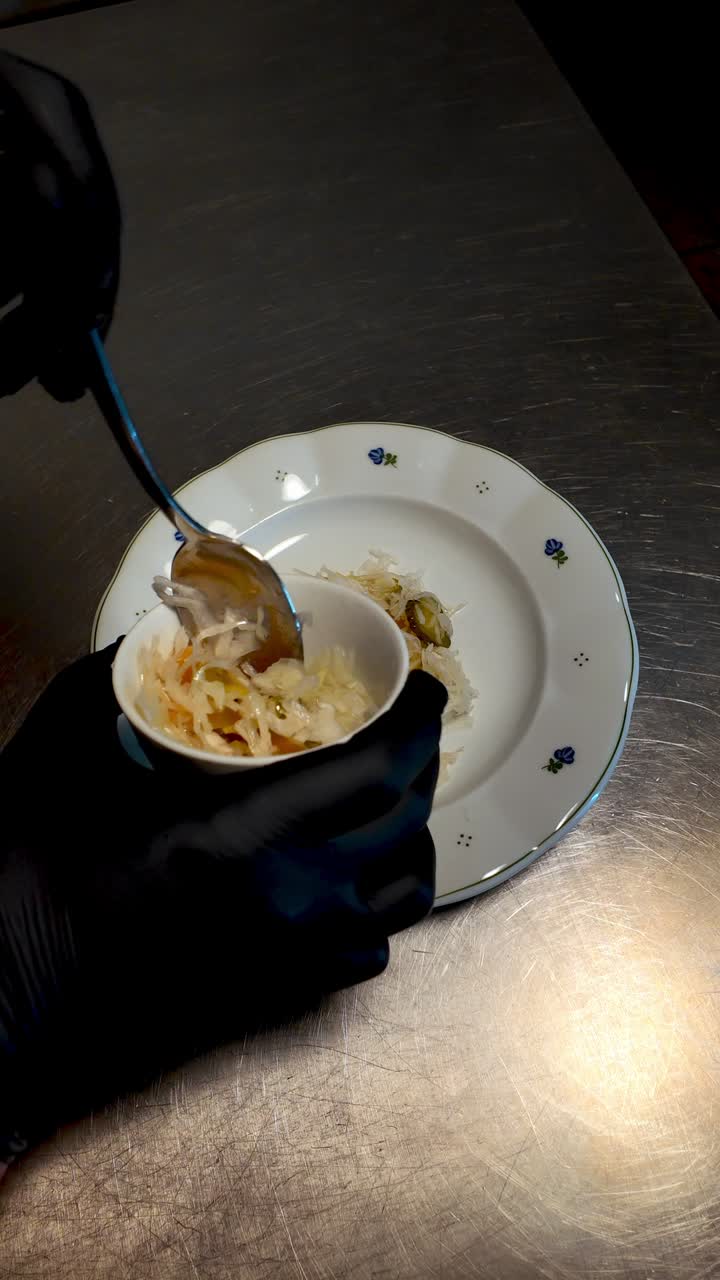 Chef serves meat delicacy with pickled vegetable garnish in restaurant kitchen. Close-up food plating ideal for menus, dining promotions, and culinary content