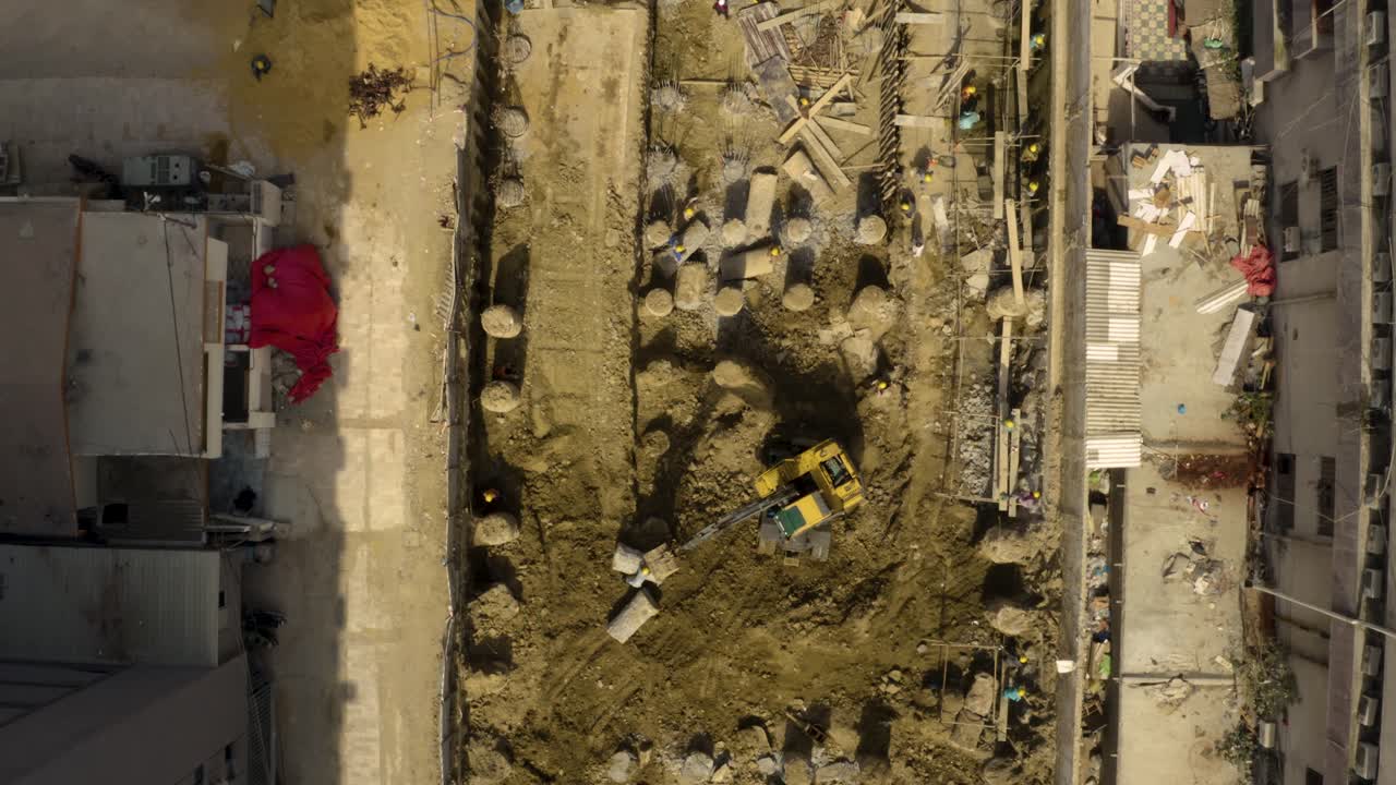 Top down aerial view of a building's foundation construction with workers and machinery