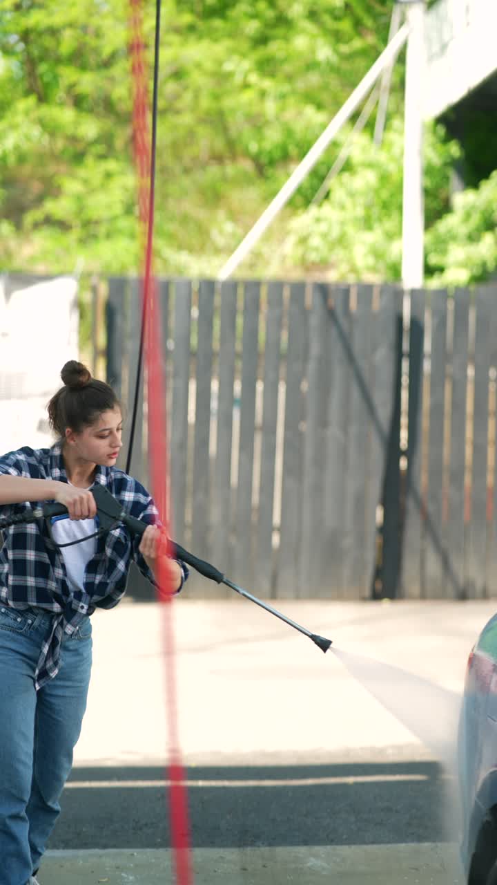 mujer lavando un coche en un lavado de coches de autoservicio