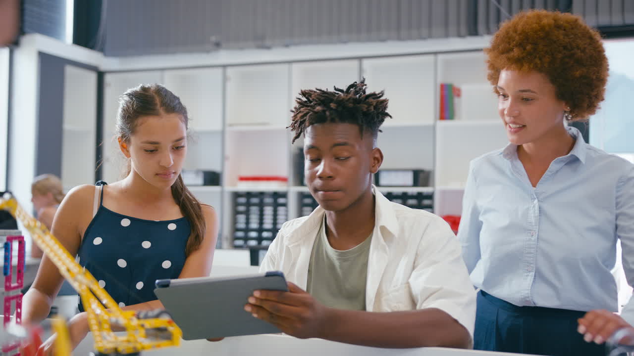 Female Teacher With High School Students Using Digital Tablet In STEM Class