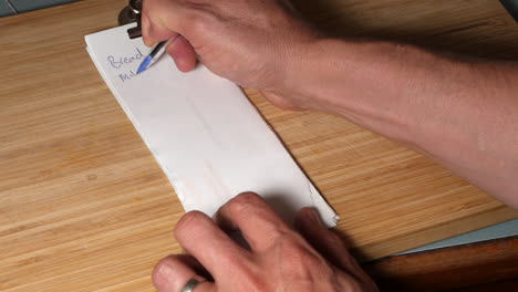 man writes shopping list on recycled paper