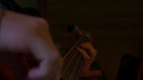 hands playing fast jazz riff on electric bass guitar, indoor close up