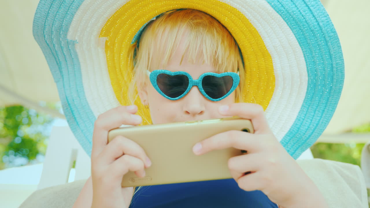 그 아이는 수영장에서 수영한 후 휴식을 취합니다 - 스마트폰에서 놀아요