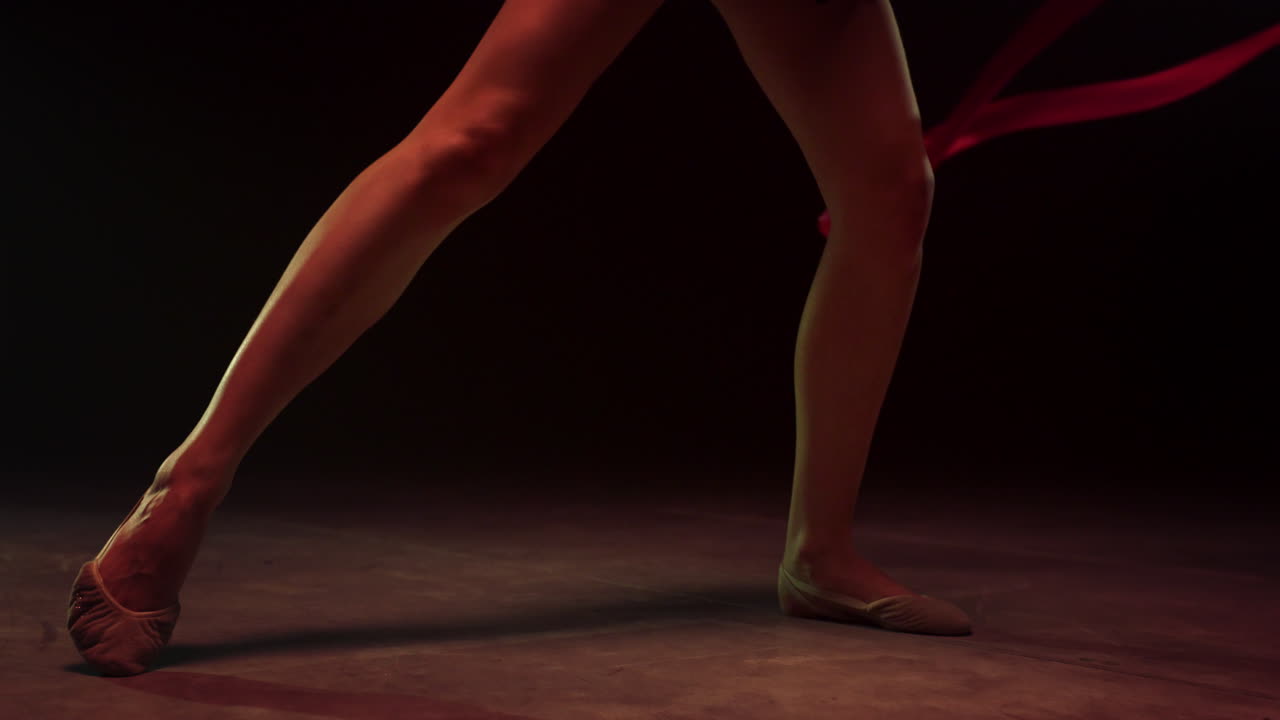 Unknown female legs practicing artistic gymnastics. Gymnast performing ribbon.