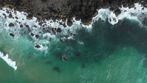 4k drone shot of ocean waves crashing on to rocky coastline and mountain cliff in australia