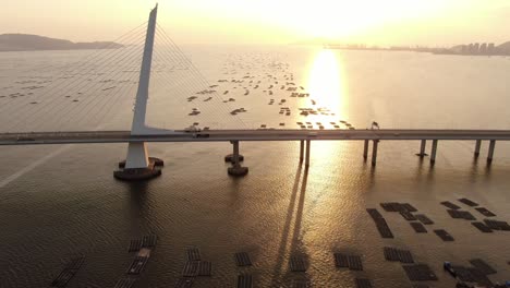 Traffic-on-Hong-Kong-Shenzhen-Bay-Bridge-at-Sunset,-with-Fish-and-Oyster-cultivation-pools,-Aerial-view