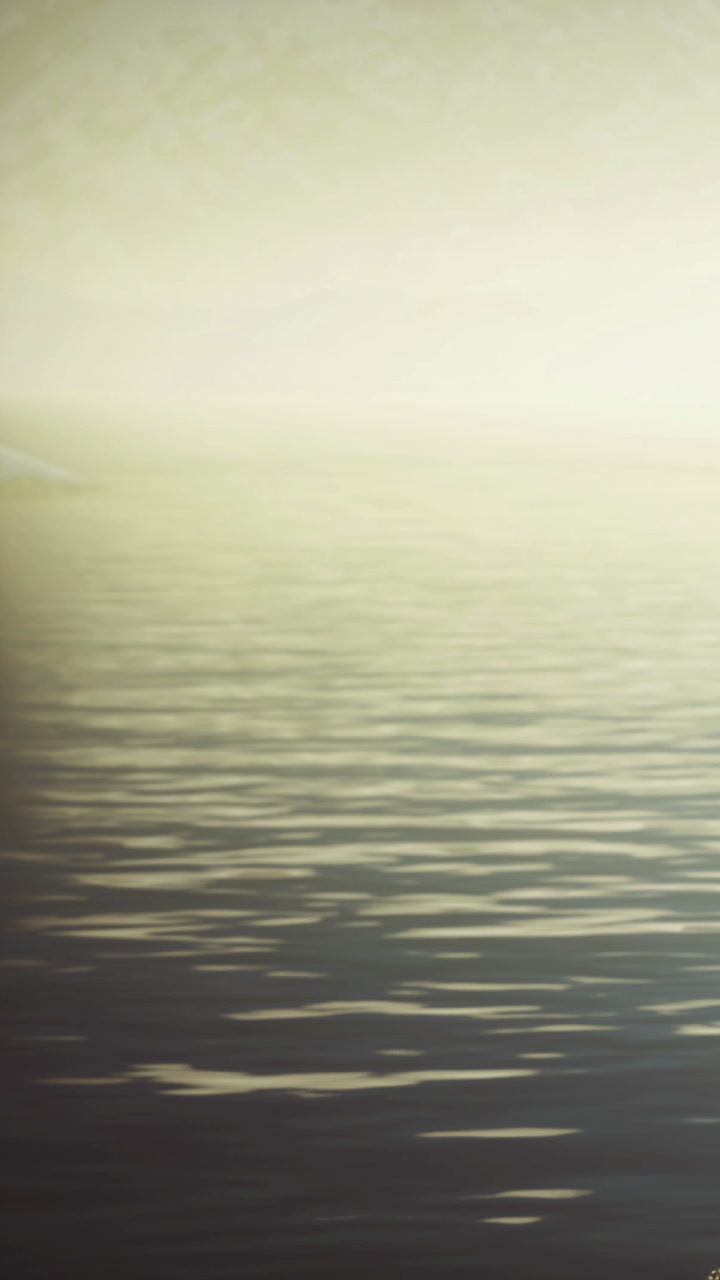 Serene misty lake at dawn with gentle ripples reflecting soft light