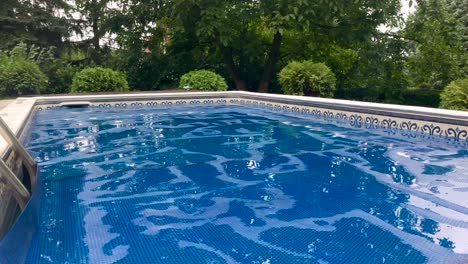 Vista-Del-Nivel-De-La-Piscina-En-La-Piscina-Enterrada-Privada-Cubierta-Solar-Con-Estanques-De-Lluvia-En-La-Superficie-De-La-Cubierta-En-4k