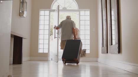 senior couple with suitcase opening front door and leaving for vacation