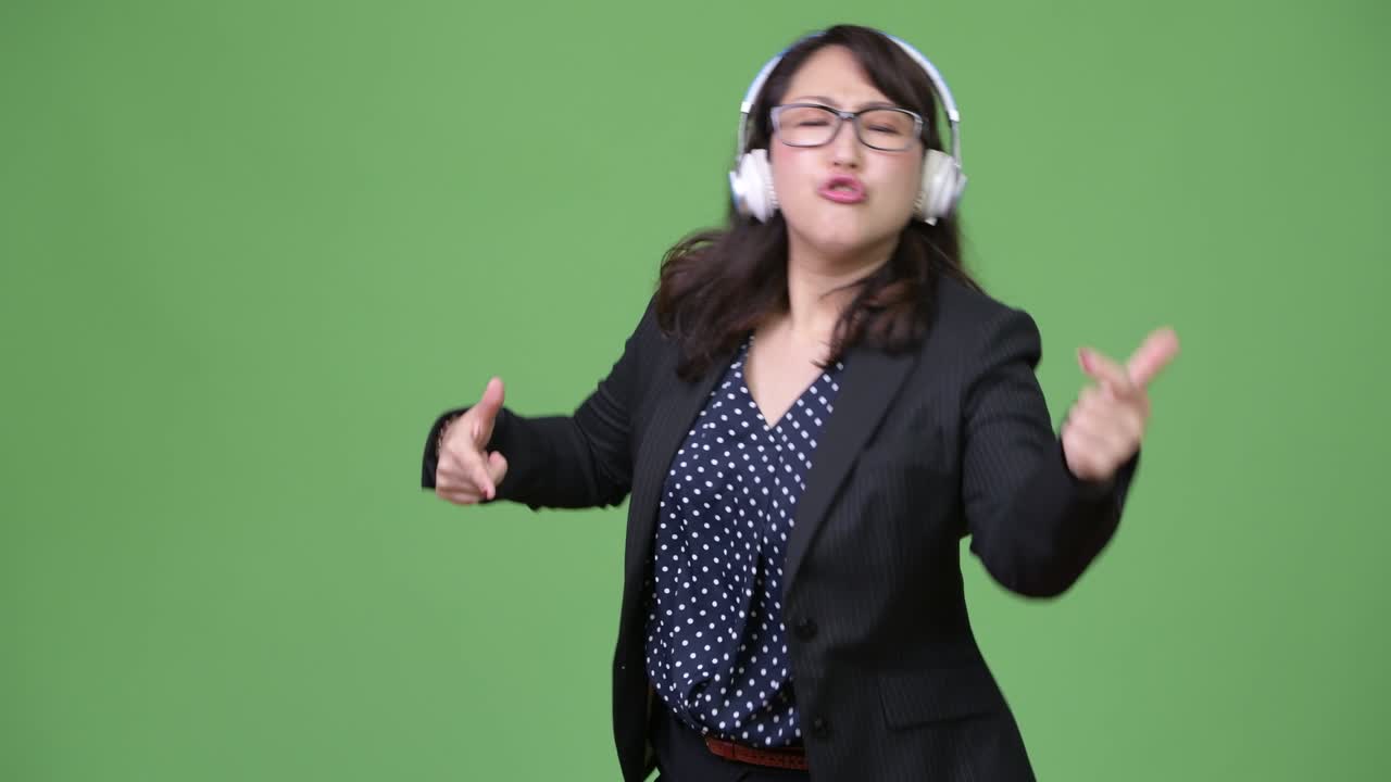 성숙하고 아름다운 아시아 사업가 여성이 음악을 듣고 있습니다.
