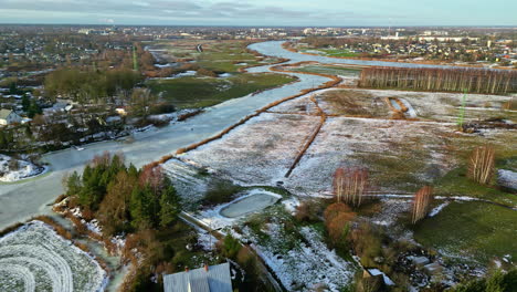 aerial drone above city at outskirts with pale blue river water frozen by winter