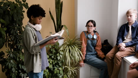 young people gathered indoors, with one reading a book