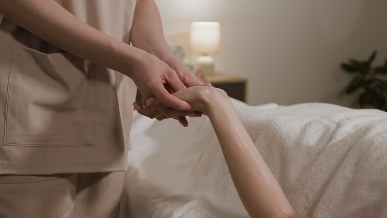 A close-up of a professional masseuse performing a hand massage on a client at a spa.