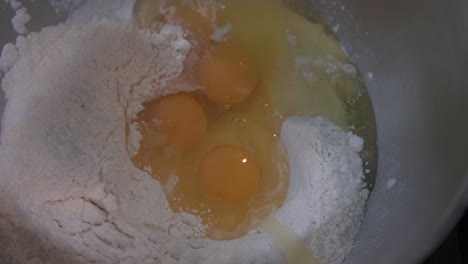 cracking eggs into flour, chef making a cake