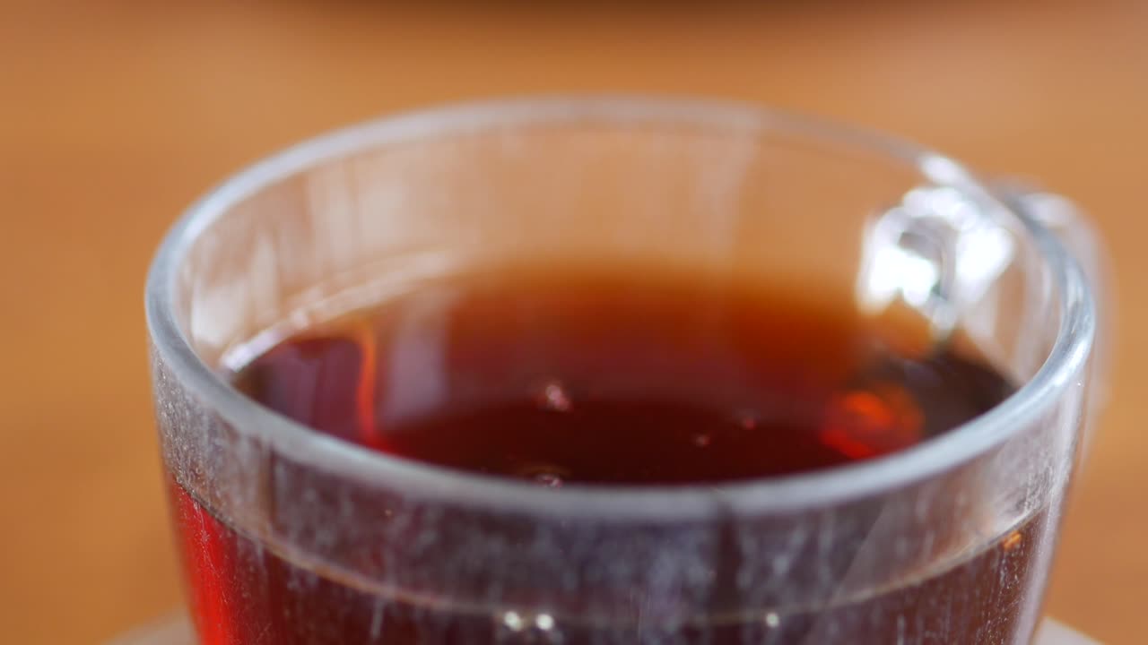 A close-up of a cup of tea being stirred with a spoon