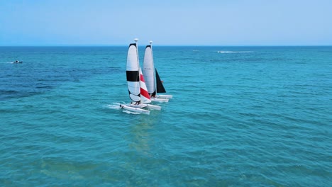 an aerial view of two catamaran sailboats are floating on the water, each with a person controlling it close together, and there is another boat further away in the background. at tunisia djerba