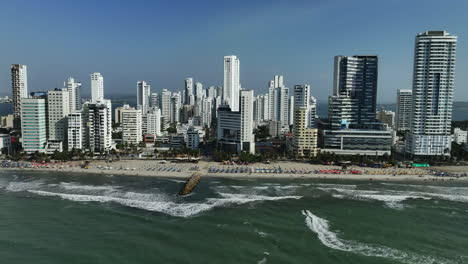 Aerial-view-of-waves-hitting-the-Playa-the-Bocagrande-beach,-in-sunny-Cartagena,-Colombia