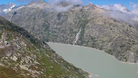 Un-Dron-Panorámico-Disparó-Sobre-Grimselsee-En-Suiza,-Mirando-El-Agua-De-Color-Menta-Hacia-Las-Montañas-Cubiertas-De-Nieve-En-El-Oeste