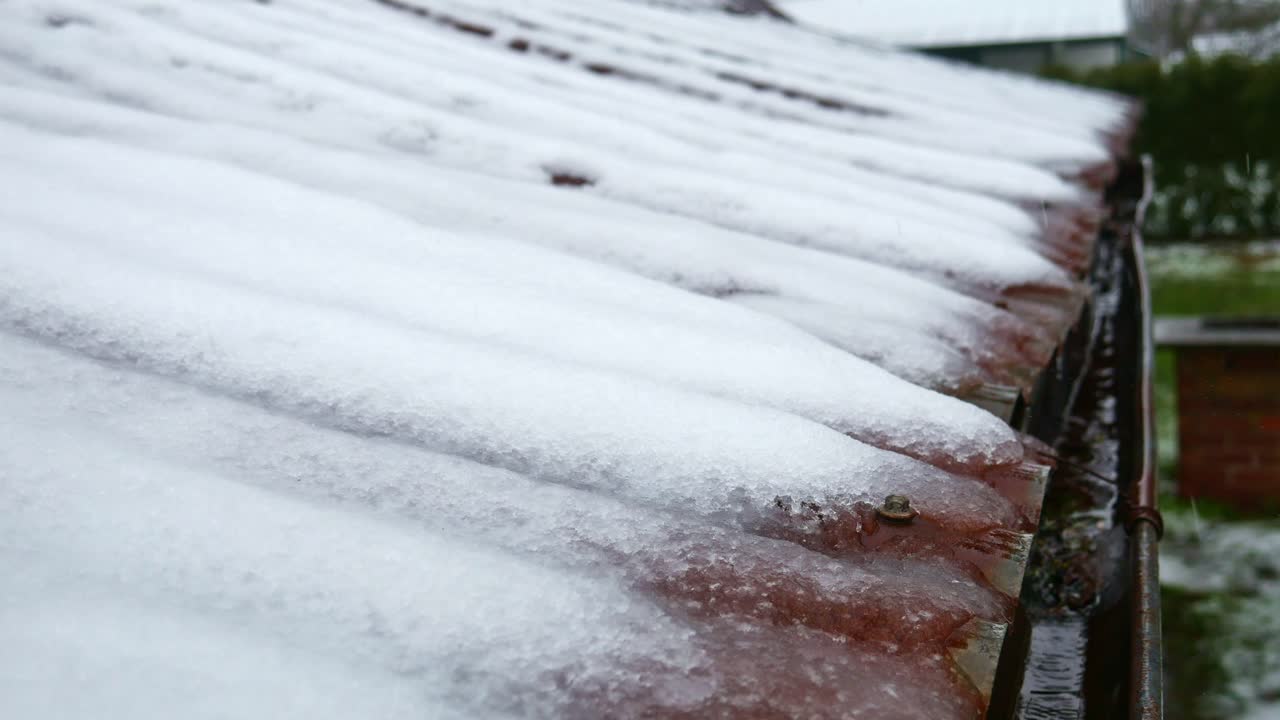 눈 덮인 주름진 철제 지붕에서 유서 깊은 광부의 오두막에 있는 홈통으로 물이 흐릅니다.