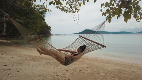 female tourist relaxes swinging in a hammock on the beach in borneo