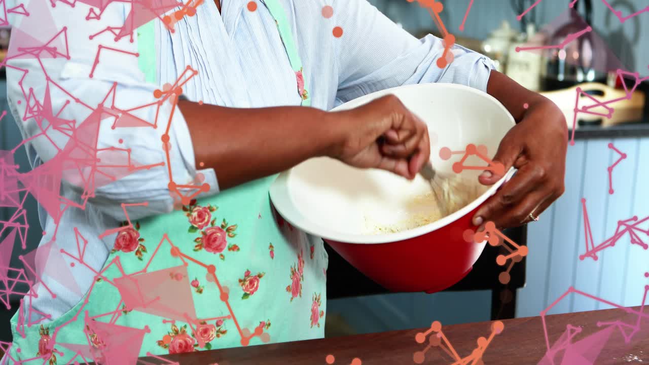Home cook dipping whisk into batter and stirring for smooth batter with drifting pink orange shapes