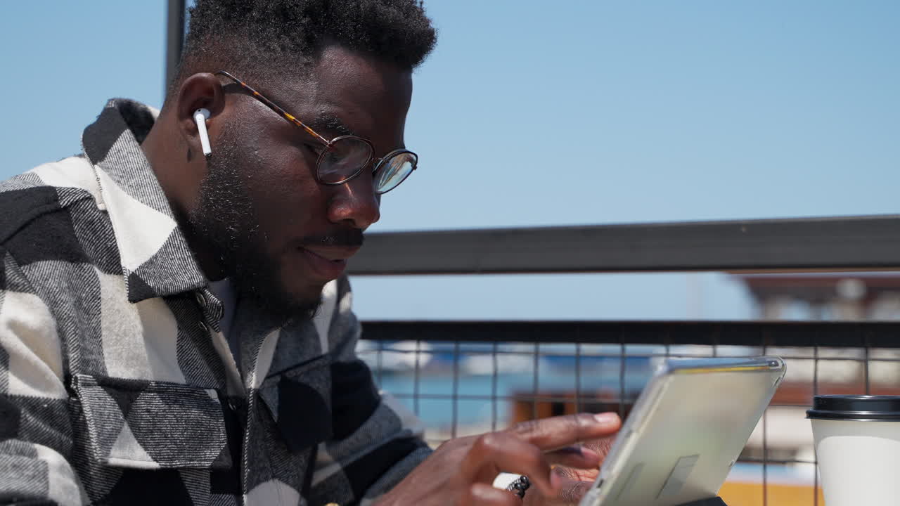 Man working on a tablet outdoors at a cafe
