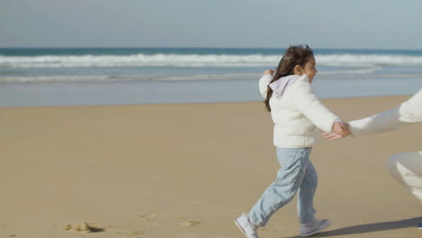 adorable little japanese girl running to her dad and falling into his arms on the beach