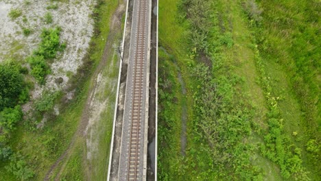 aerial reverse footage over a railway revealing a wetland below and some pockets of water, farmlands