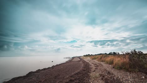 Nubes-Tormentosas-Que-Se-Mueven-Rápidamente-Sobre-La-Playa-De-Guijarros-En-El-Vídeo-Timelapse