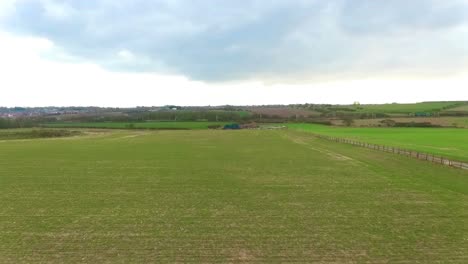 drone flight across fields starting low and going higher crossing train tracks. the train line cuts through the green belt providing key transportation