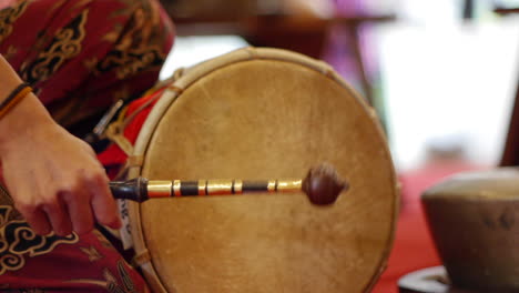 traditional south east asian skinned drum played with wooden mallet, filmed as close up in handheld style